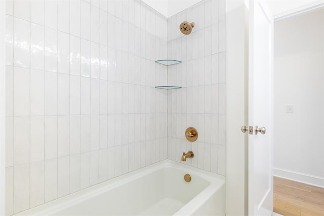 bathroom with hardwood / wood-style floors and tiled shower / bath