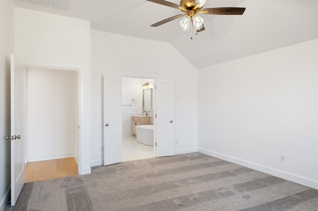 unfurnished bedroom with connected bathroom, light colored carpet, vaulted ceiling, and ceiling fan