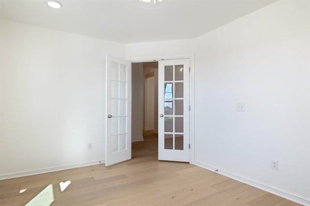 unfurnished room featuring french doors and light wood-type flooring