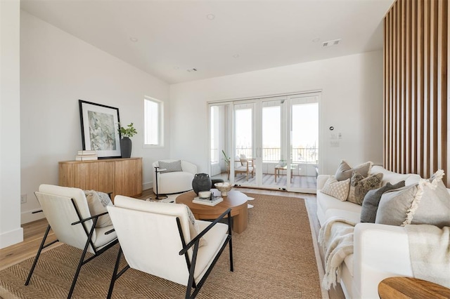 living room with light hardwood / wood-style floors, a wealth of natural light, and french doors