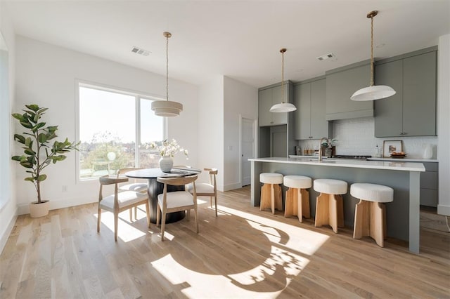 kitchen with tasteful backsplash, gray cabinetry, and light wood-type flooring