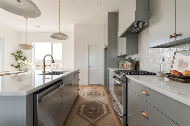 kitchen featuring sink, hanging light fixtures, stainless steel appliances, an island with sink, and custom range hood