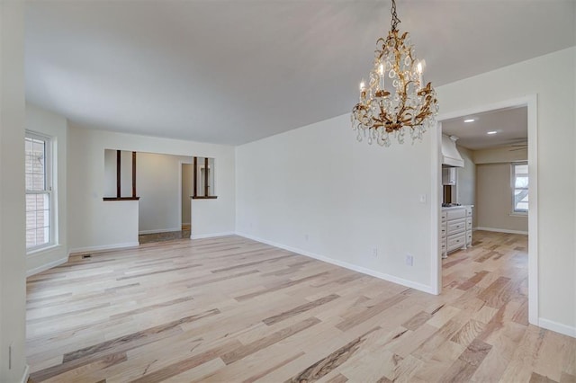 unfurnished room featuring light hardwood / wood-style floors and an inviting chandelier