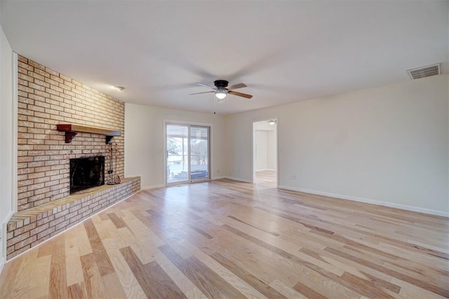 unfurnished living room featuring ceiling fan, light wood-type flooring, and a brick fireplace