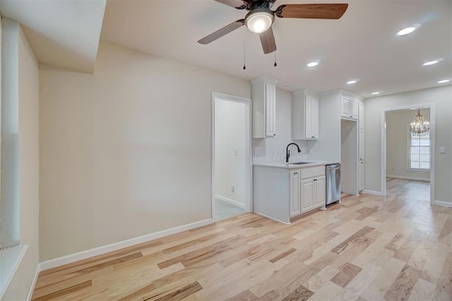 kitchen with stainless steel dishwasher, light hardwood / wood-style floors, decorative backsplash, white cabinets, and ceiling fan with notable chandelier