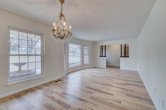 unfurnished room featuring a notable chandelier and light hardwood / wood-style floors