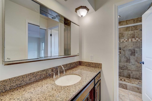 bathroom featuring a tile shower, tile patterned flooring, and vanity