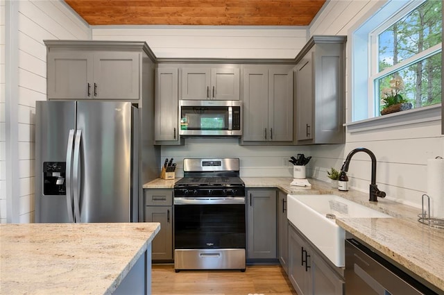 kitchen with stainless steel appliances, light stone counters, wood ceiling, and sink