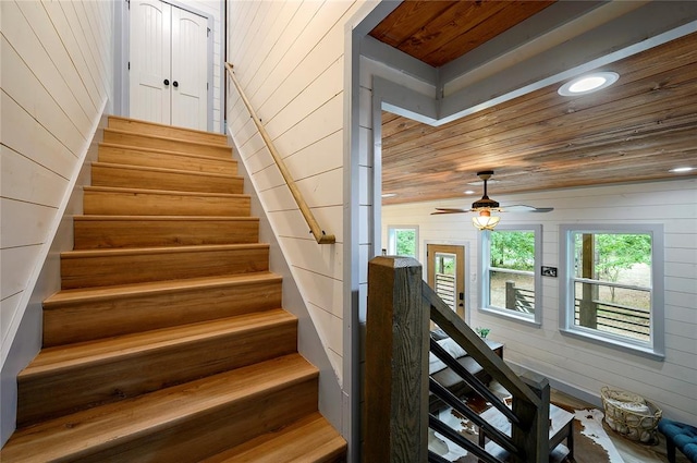 stairs featuring hardwood / wood-style floors, wooden walls, vaulted ceiling, ceiling fan, and wood ceiling