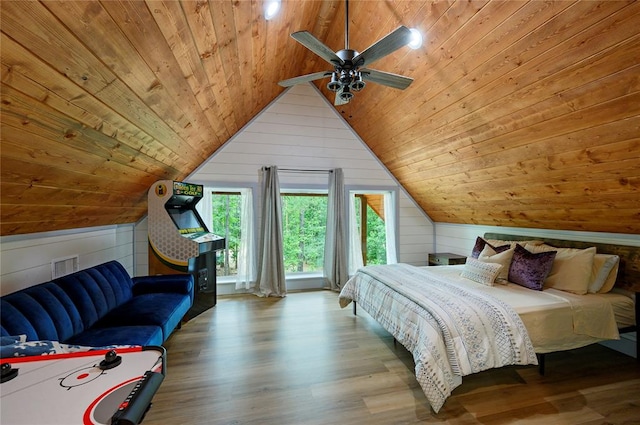 bedroom featuring ceiling fan, wooden walls, wooden ceiling, hardwood / wood-style floors, and lofted ceiling