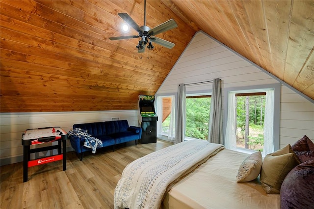 bedroom featuring wood walls, vaulted ceiling, and light wood-type flooring