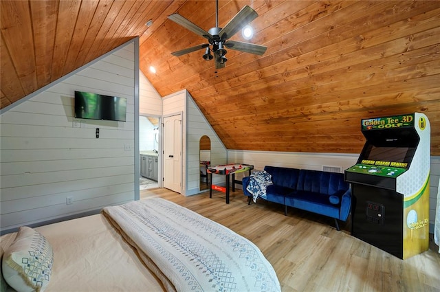 bedroom with light wood-type flooring, wooden walls, ceiling fan, and lofted ceiling