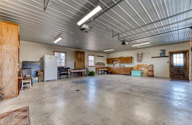 garage featuring a workshop area, a garage door opener, and white refrigerator