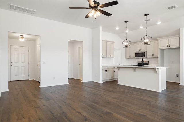 kitchen with stainless steel appliances, an island with sink, and dark wood-type flooring