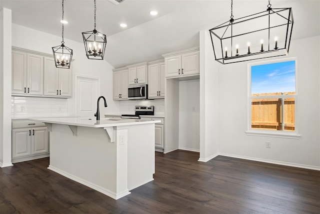 kitchen featuring dark hardwood / wood-style flooring, a breakfast bar, stainless steel appliances, white cabinetry, and an island with sink