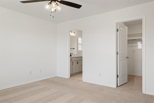 unfurnished bedroom with ensuite bath, light colored carpet, ceiling fan, a spacious closet, and a closet