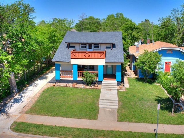 view of front facade with a balcony, covered porch, and a front yard