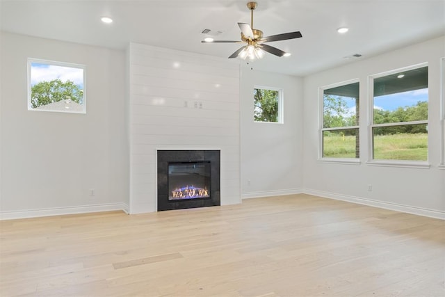 unfurnished living room featuring a fireplace, light wood-type flooring, and ceiling fan