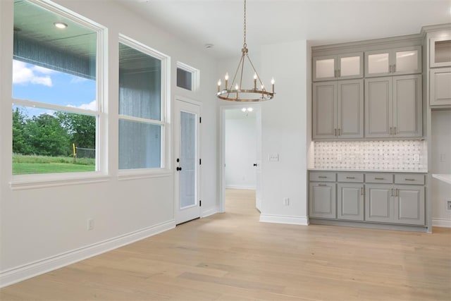 unfurnished dining area with a chandelier and light wood-type flooring