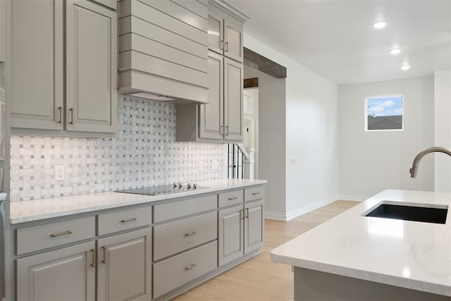 kitchen featuring black electric stovetop, gray cabinetry, custom range hood, sink, and light hardwood / wood-style floors