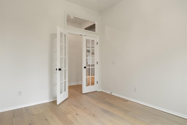 spare room with french doors and light hardwood / wood-style floors