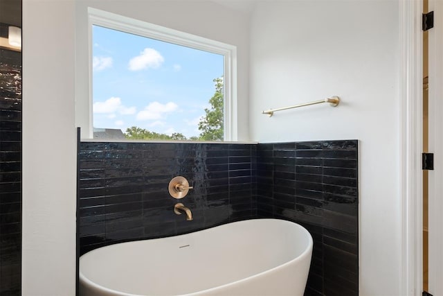 bathroom with a tub and tile walls