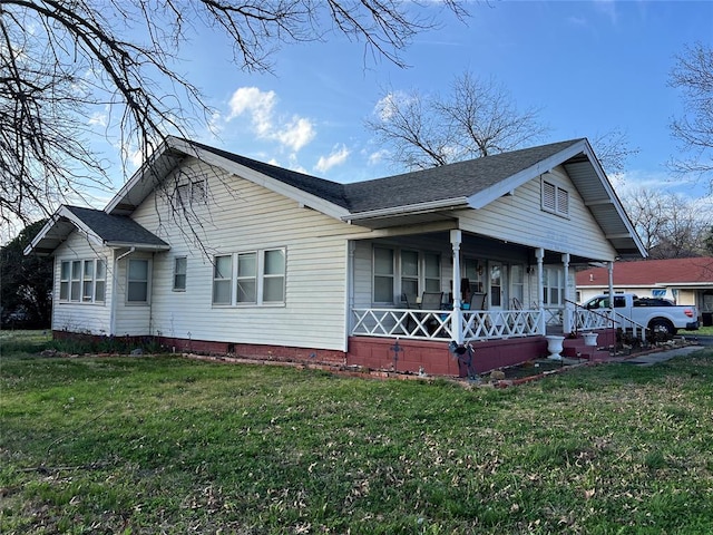 view of side of property with a porch and a lawn