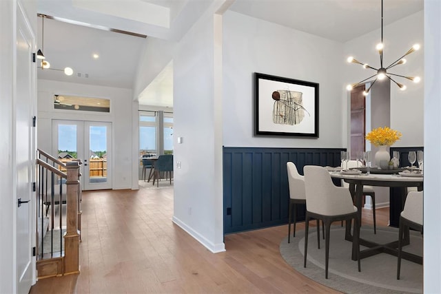 dining space with french doors, lofted ceiling with beams, light hardwood / wood-style flooring, and a notable chandelier