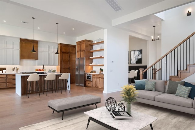 living room featuring vaulted ceiling, light hardwood / wood-style flooring, and a notable chandelier