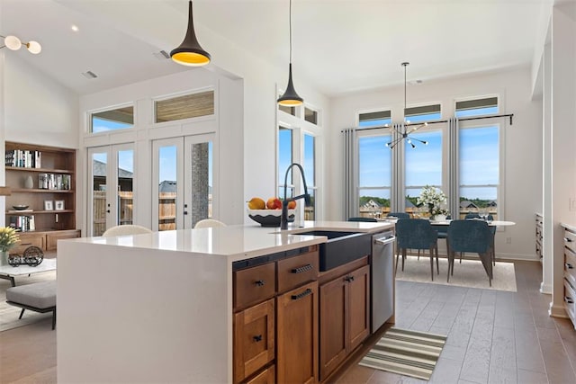 kitchen with sink, an inviting chandelier, pendant lighting, light hardwood / wood-style floors, and a center island with sink