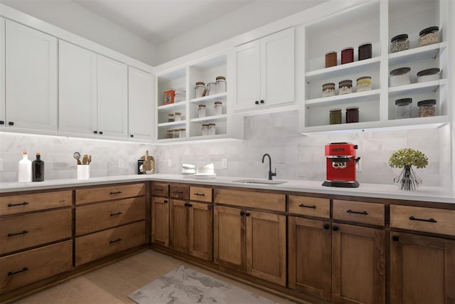 kitchen featuring decorative backsplash, sink, white cabinets, and light hardwood / wood-style flooring