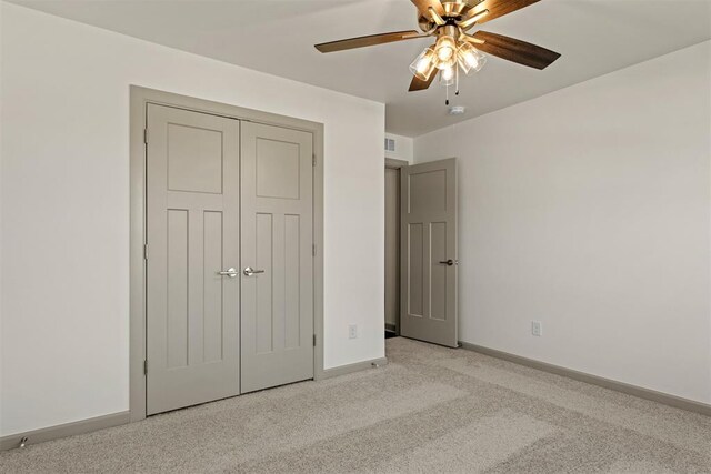 unfurnished bedroom with ceiling fan, a closet, and light colored carpet