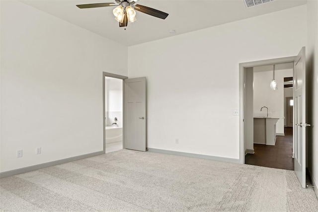 unfurnished bedroom with ceiling fan, carpet floors, and ensuite bathroom