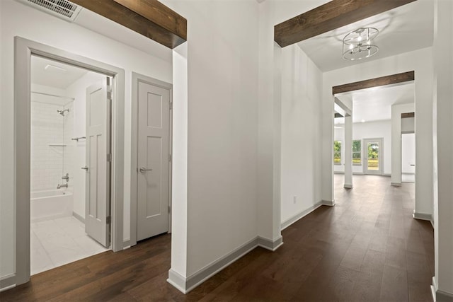 corridor featuring dark wood-type flooring and an inviting chandelier