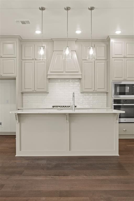 kitchen with a center island with sink, dark hardwood / wood-style floors, and stainless steel appliances