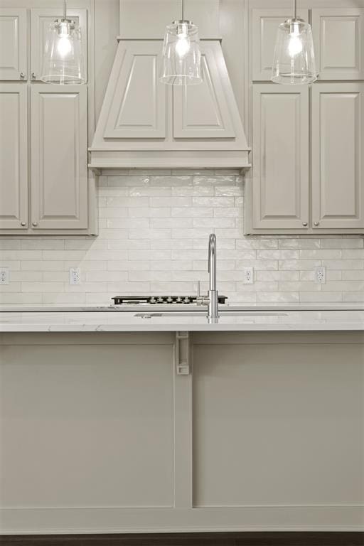 kitchen featuring white cabinets, custom exhaust hood, decorative backsplash, and hanging light fixtures