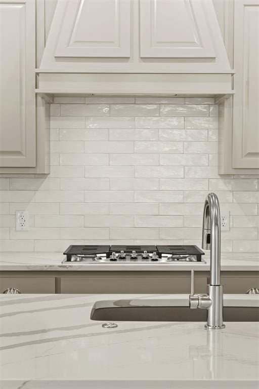 details with white cabinetry, backsplash, and light stone countertops