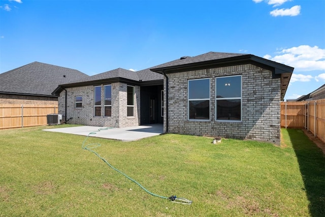 rear view of property featuring a lawn, central AC, and a patio area