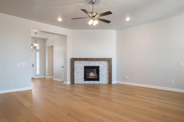 unfurnished living room with a tile fireplace, light hardwood / wood-style floors, and ceiling fan