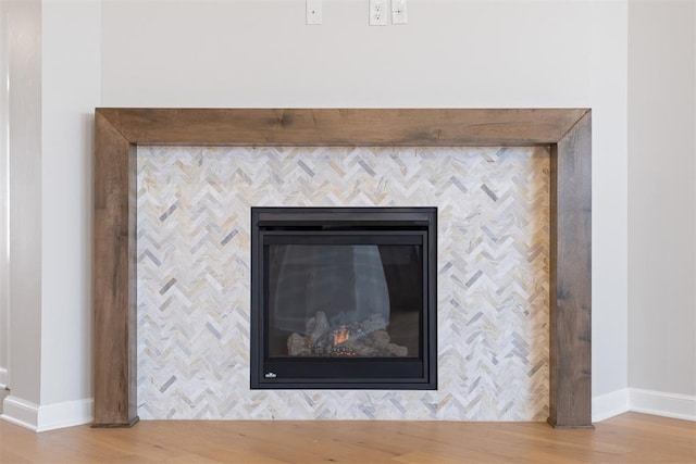 interior details with a tile fireplace and hardwood / wood-style flooring