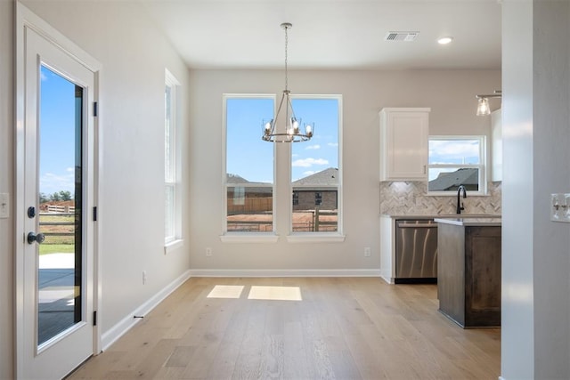 unfurnished dining area featuring plenty of natural light, light hardwood / wood-style flooring, and an inviting chandelier