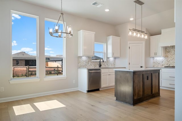 kitchen featuring hanging light fixtures, white cabinets, stainless steel dishwasher, and light hardwood / wood-style floors