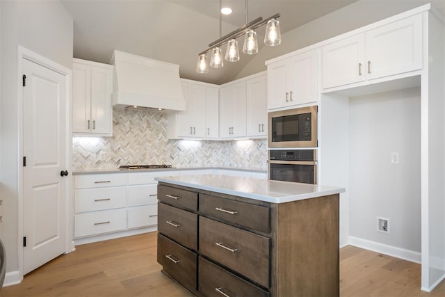 kitchen with white cabinetry, light hardwood / wood-style floors, pendant lighting, appliances with stainless steel finishes, and custom exhaust hood