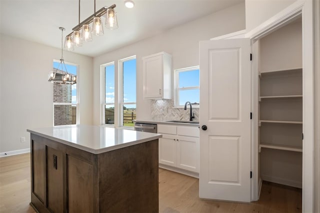 kitchen featuring white cabinetry, sink, pendant lighting, light hardwood / wood-style floors, and decorative backsplash