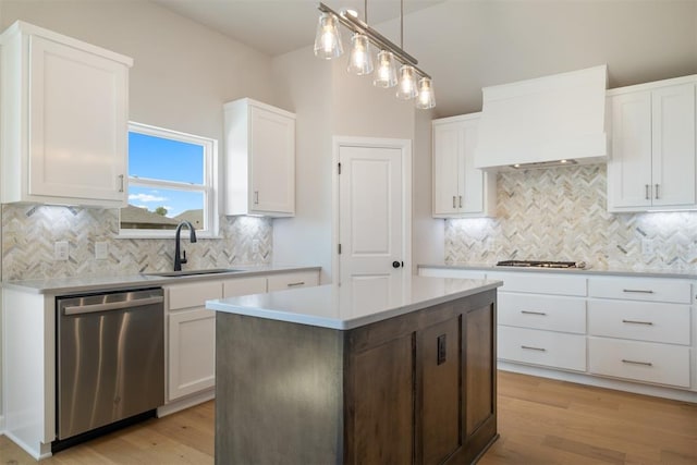 kitchen featuring appliances with stainless steel finishes, sink, light hardwood / wood-style flooring, white cabinets, and a kitchen island