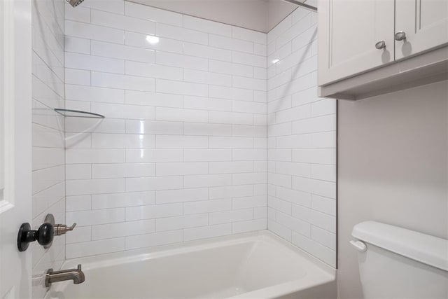 bathroom with tiled shower / bath combo and toilet