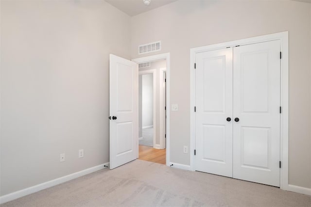 unfurnished bedroom with a closet and light colored carpet