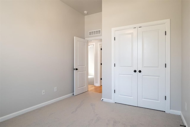 unfurnished bedroom featuring light colored carpet and a closet