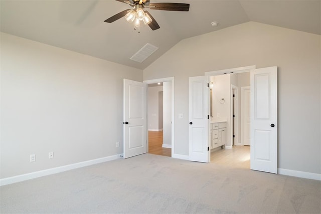 unfurnished bedroom with ensuite bath, ceiling fan, light carpet, and vaulted ceiling