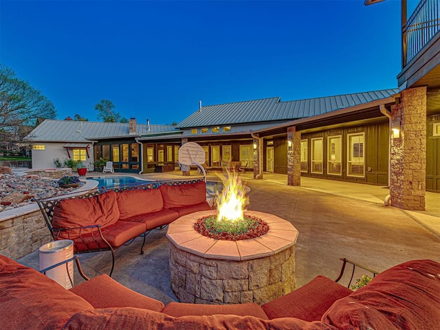 patio terrace at dusk with a balcony and an outdoor living space with a fire pit